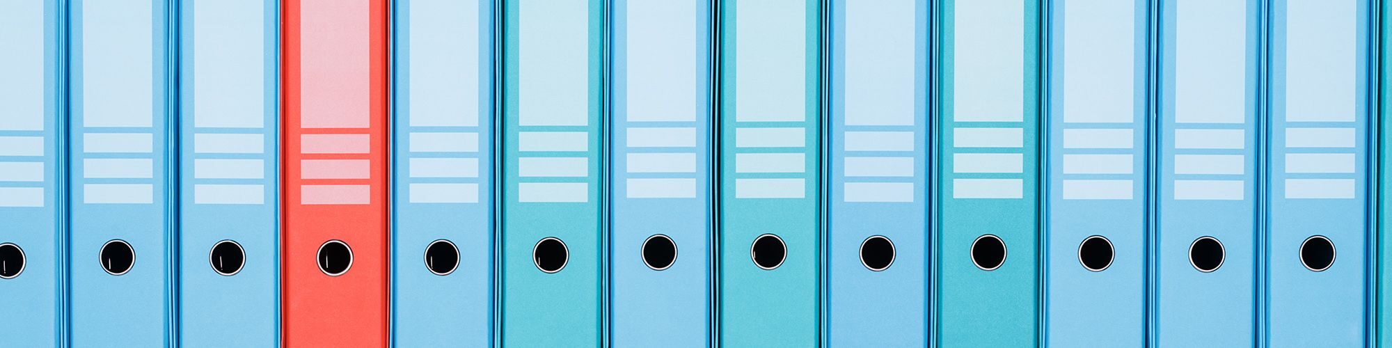 Une ligne de classeurs de couleur bleue, rouge et cyan.