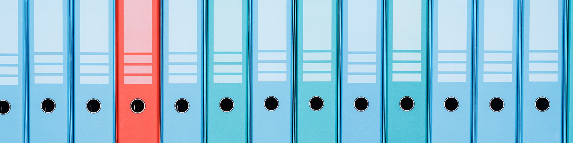 Une ligne de classeurs de couleur bleue, rouge et cyan.