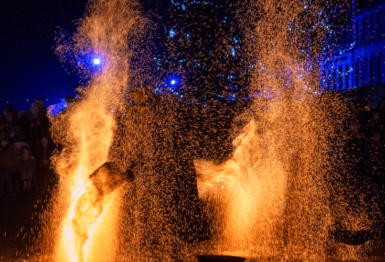 Un spectacle de feu, avec des braises partout qui recouvre une personne (avec des protections).