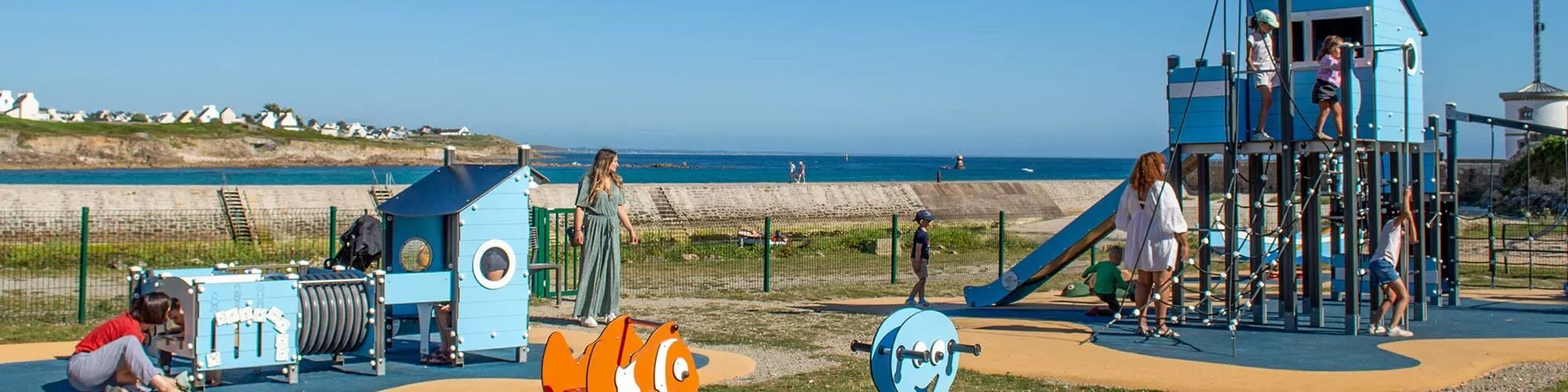 Enfants qui jouent sur la plaine sportive, sous le regards de leurs mères.