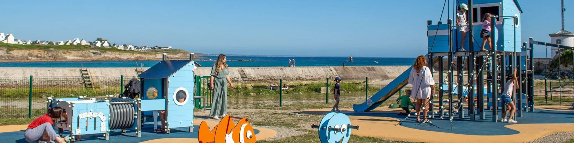Enfants qui jouent sur la plaine sportive, sous le regards de leurs mères.