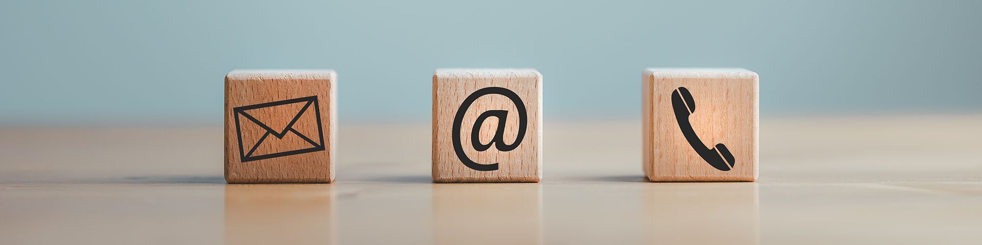 Des cubes de bois avec sur chacun un symbole, une lettre (mail), un arobase, un téléphone.