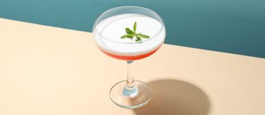 Verre à pied, rempli d'alcool, posé sur une table.
