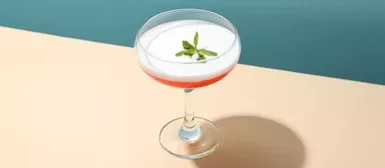 Verre à pied, rempli d'alcool, posé sur une table.