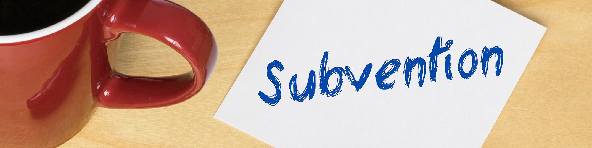 Bureau, avec tasse à café, un stylo et un post it sur lequel est noté 