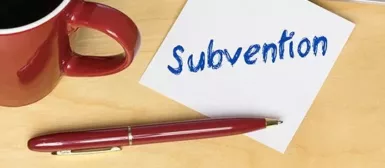 Bureau, avec tasse à café, un stylo et un post it sur lequel est noté 