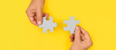 Deux main avec des pièces de puzzle, sur fond jaune.