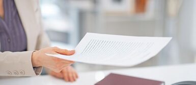 Bras d'une femme qui tend un document au-dessus d'un bureau.