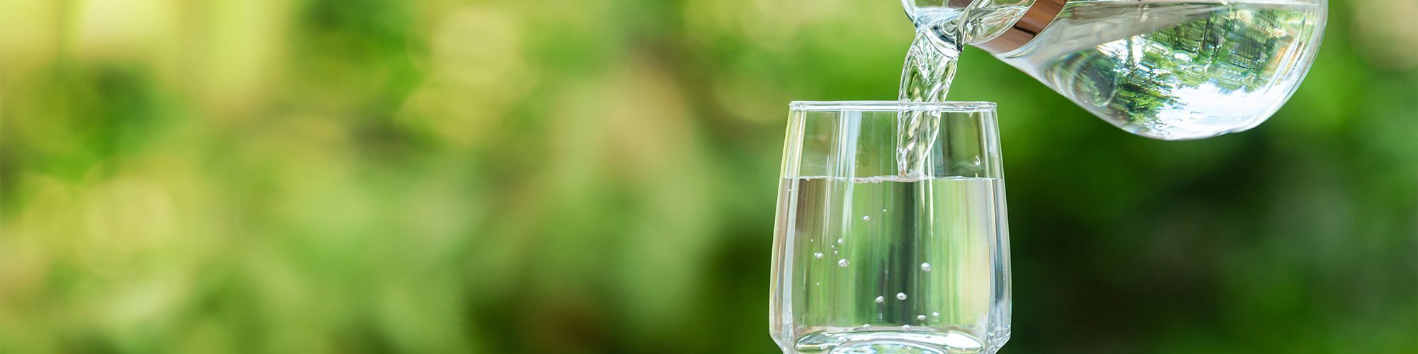 Quelqu'un qui verse de l'eau depuis une carafe dans un verre.