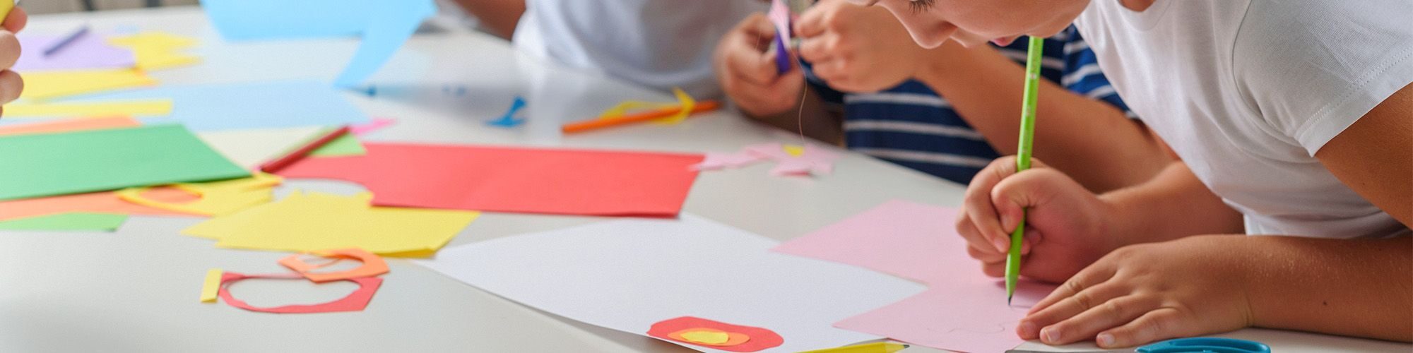 Des enfants qui découpent des feuilles et dessinent.