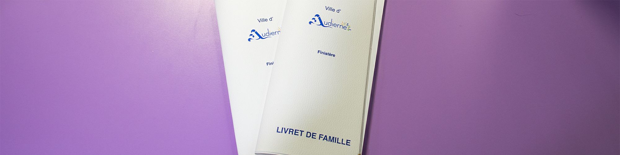 Deux livrets de famille, blancs avec le logo de la ville d'Audierne, et la mention Finistère. Les deux livrets sont superposés sur fond violet.
