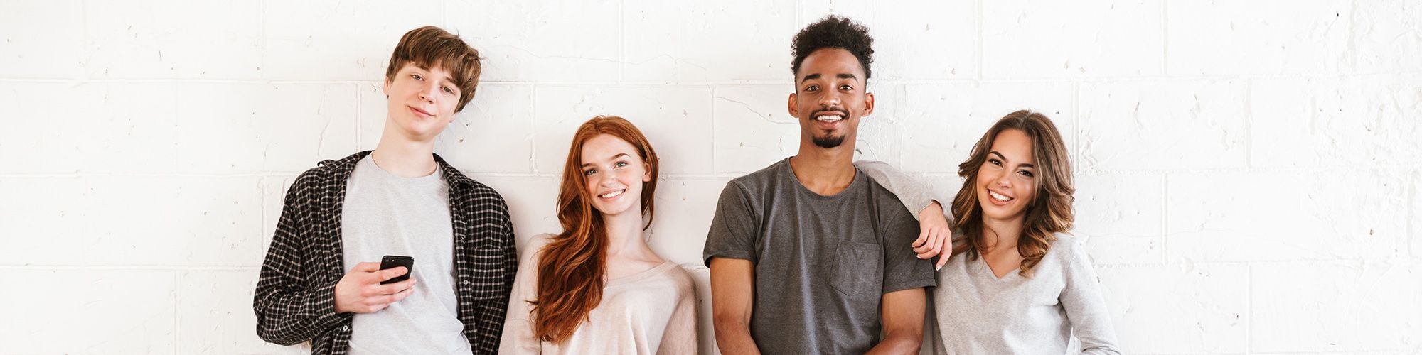 Quatre jeunes souriants, deux garçons et deux filles.