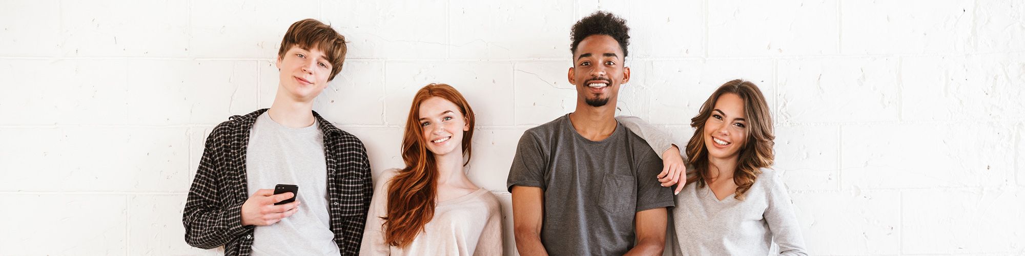 Quatre jeunes souriants, deux garçons et deux filles.