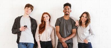 Quatre jeunes souriants, deux garçons et deux filles.