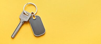 Une clé et un badge magnétique sur un porte-clés, sur fond jaune.