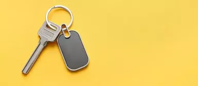 Une clé et un badge magnétique sur un porte-clés, sur fond jaune.
