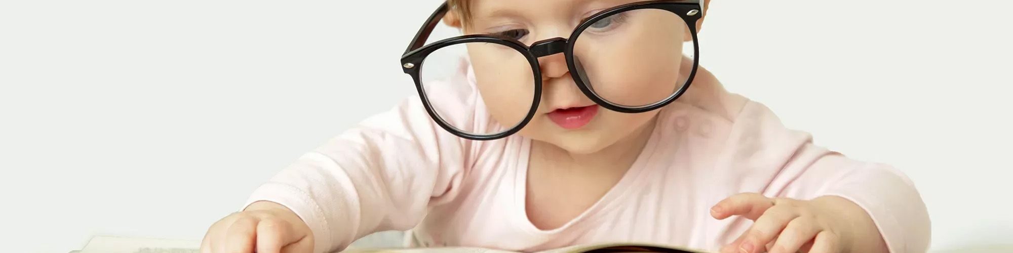 Un petit enfant qui lit un livre avec des lunettes d'adulte.