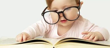 Un petit enfant qui lit un livre avec des lunettes d'adulte.