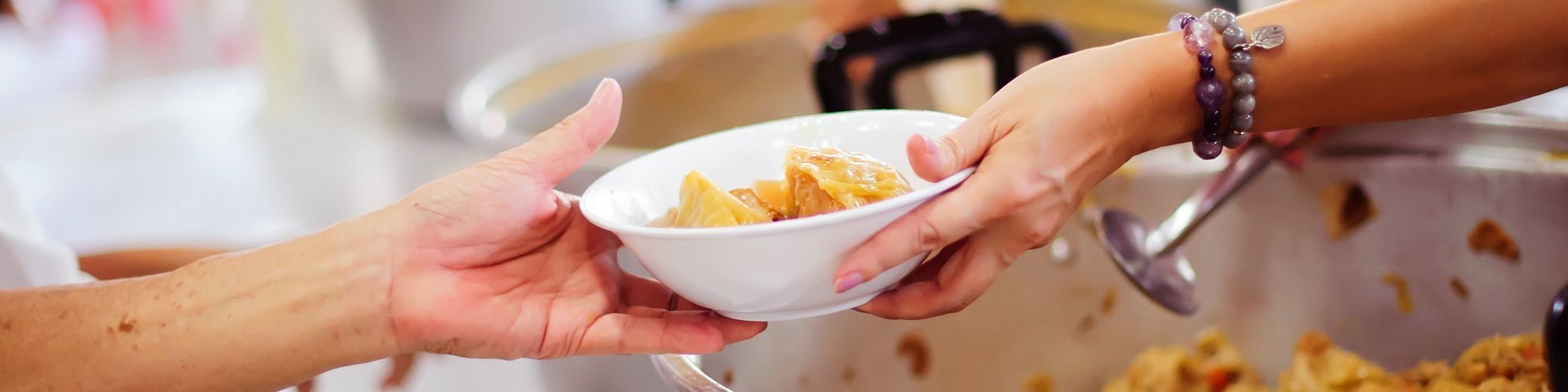 Une personne qui sert un repas à un usager.