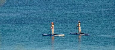 Deux femmes faisant du paddle sur une mer calme.