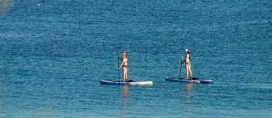 Deux femmes faisant du paddle sur une mer calme.