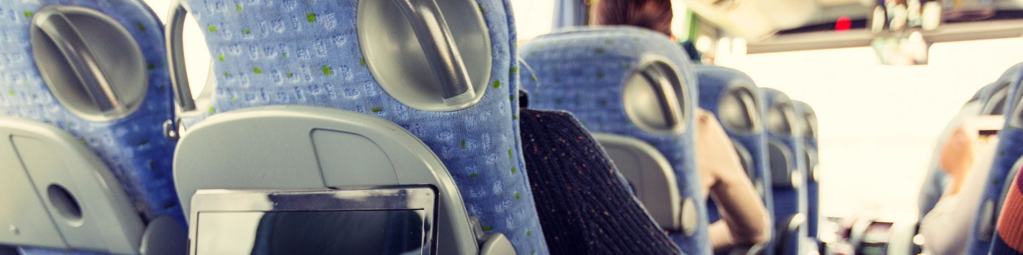 Sièges de car bleu, dans un car, on peut voir plusieurs personnes assisent.