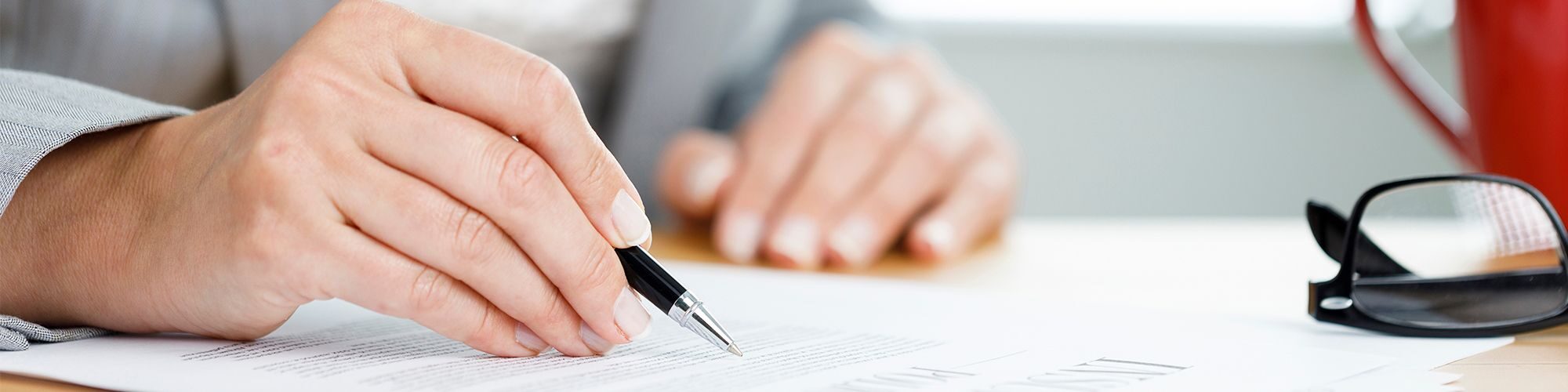 Zoom sur les bras d'une personne qui signe des documents.