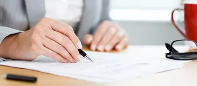 Zoom sur les bras d'une personne qui signe des documents.